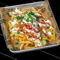 Talkin' Tacos loaded fries with white sauce, guacamole, red sprinkles, and cilantro on a tray.