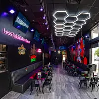 The vibrant interior of Talkin' Tacos restaurant, featuring neon signs, colorful murals, and modern seating.